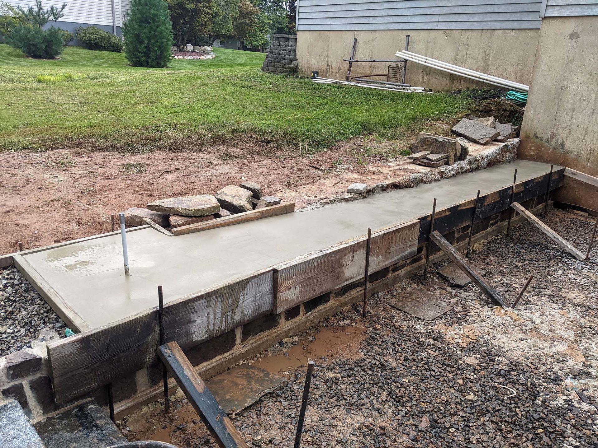 Freshly poured concrete in forms; a construction project near a house and lawn.