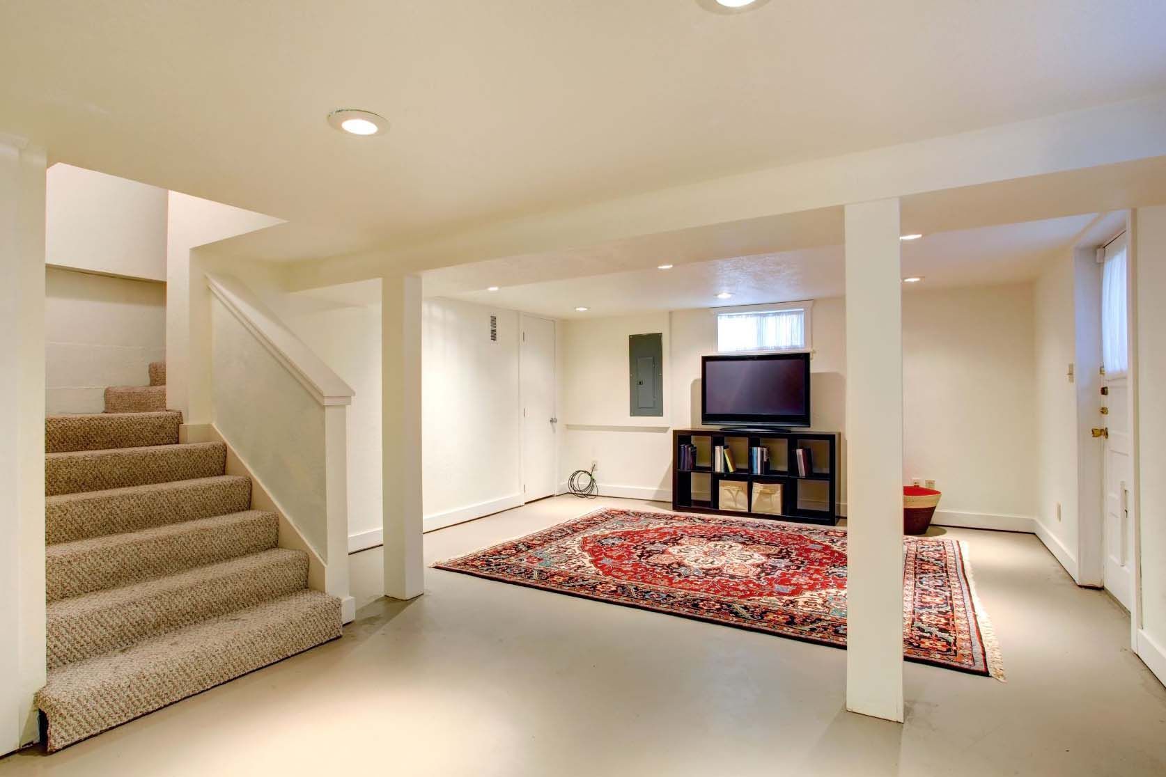 Basement living area with carpeted stairs, columns, rug, TV, and recessed lighting.