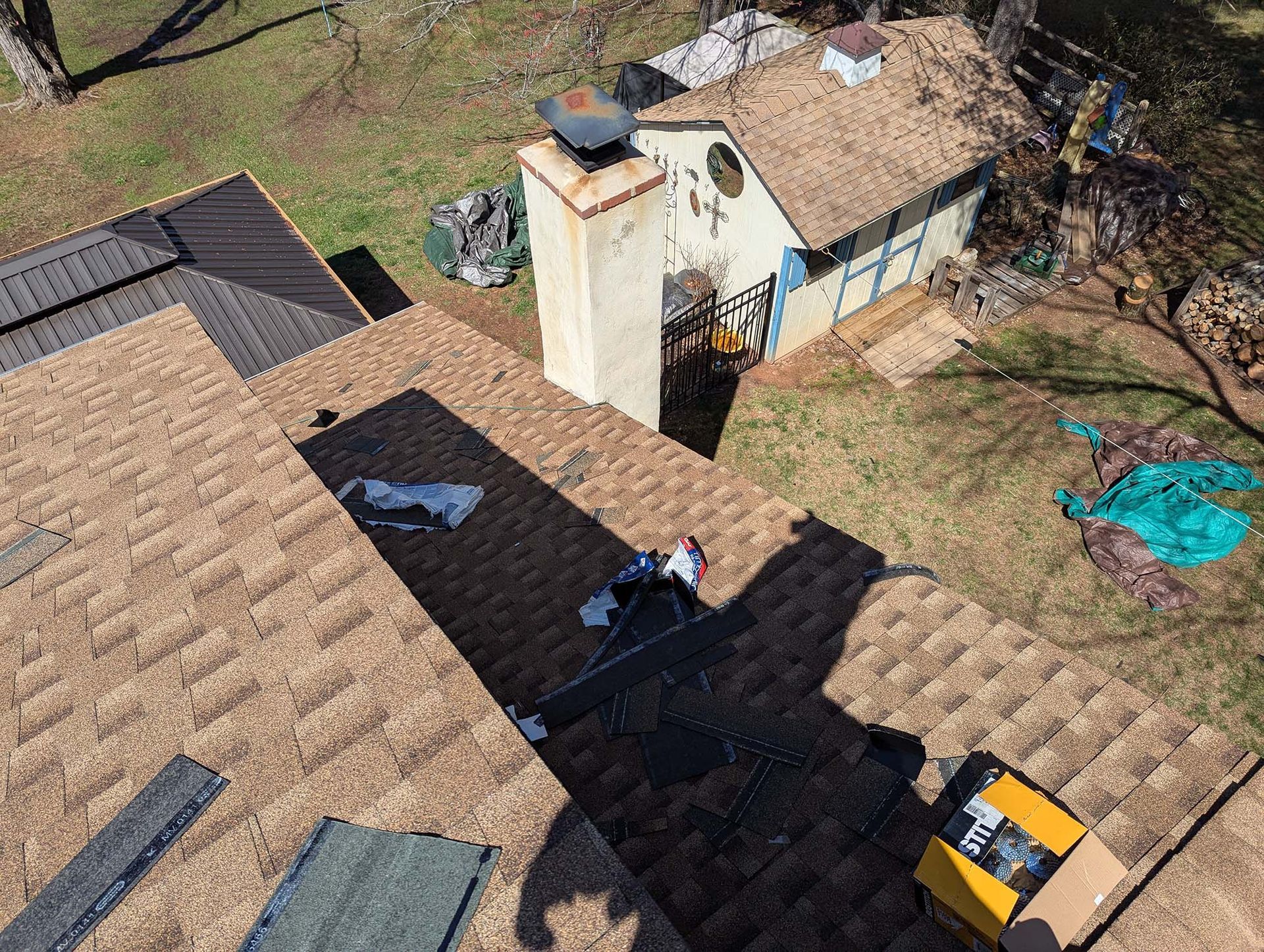 Overhead view of a roof with a person working on it, surrounded by tools and equipment.
