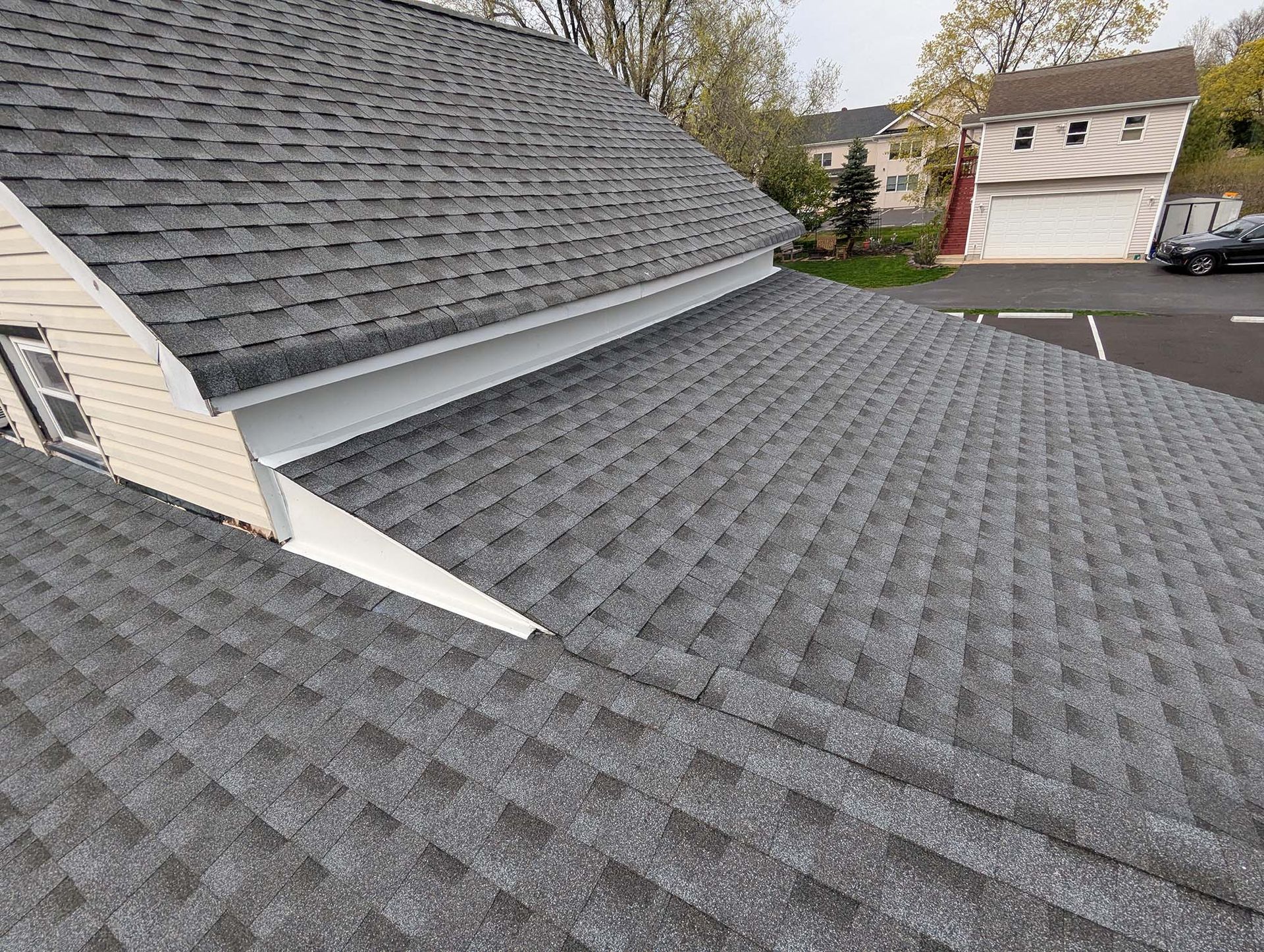 Gray asphalt shingle roof on a house, angled view of the shingles and trim work.