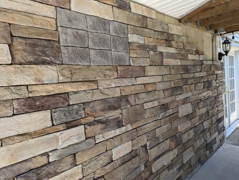 Stone facade on building exterior, with a patch of mismatched blocks, under a roof.