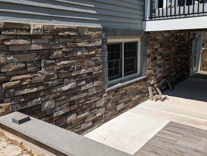 Stone veneer exterior wall with a window, beneath a balcony.
