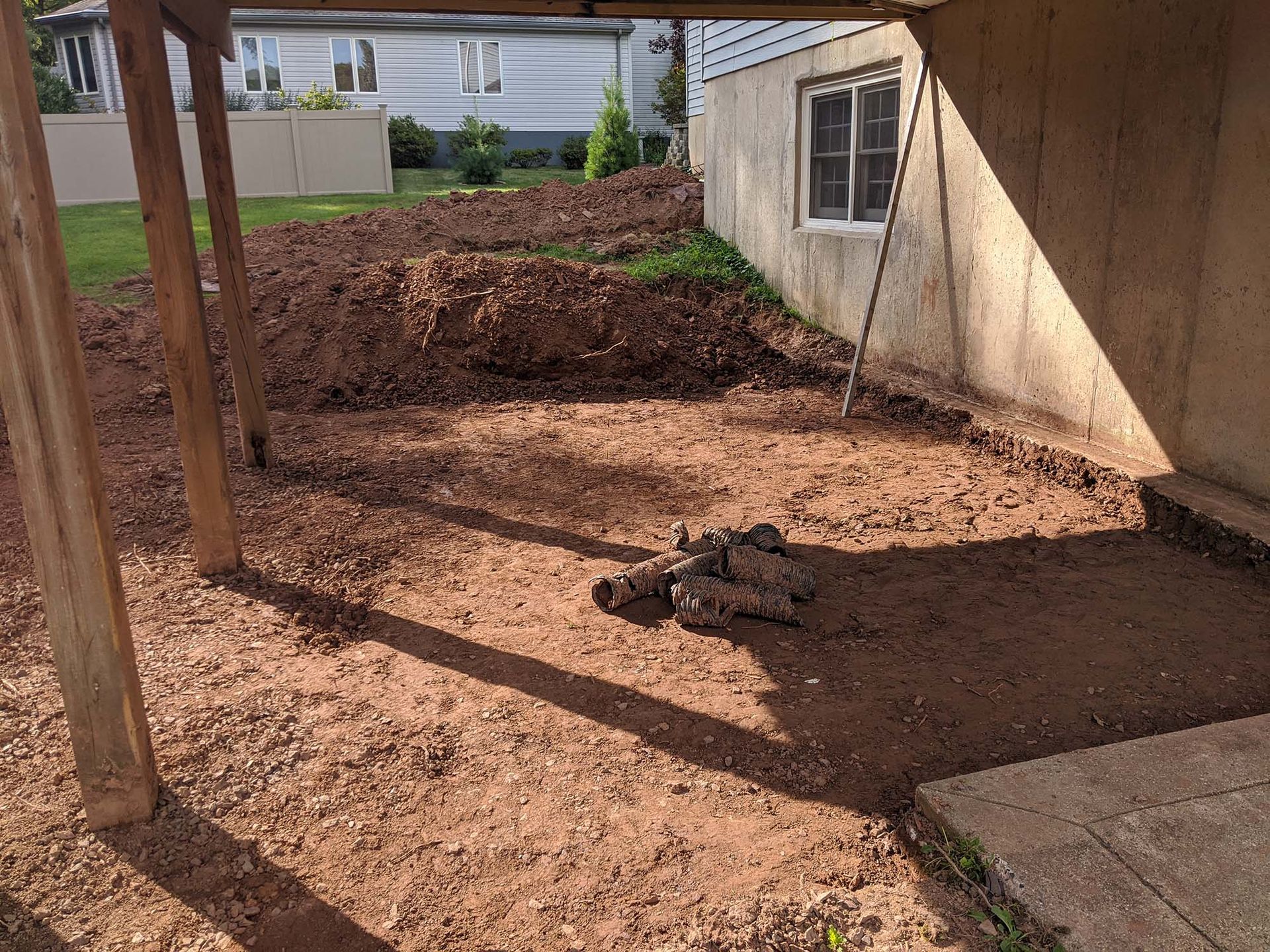 Dirt ground area under a house foundation with wood support beams.