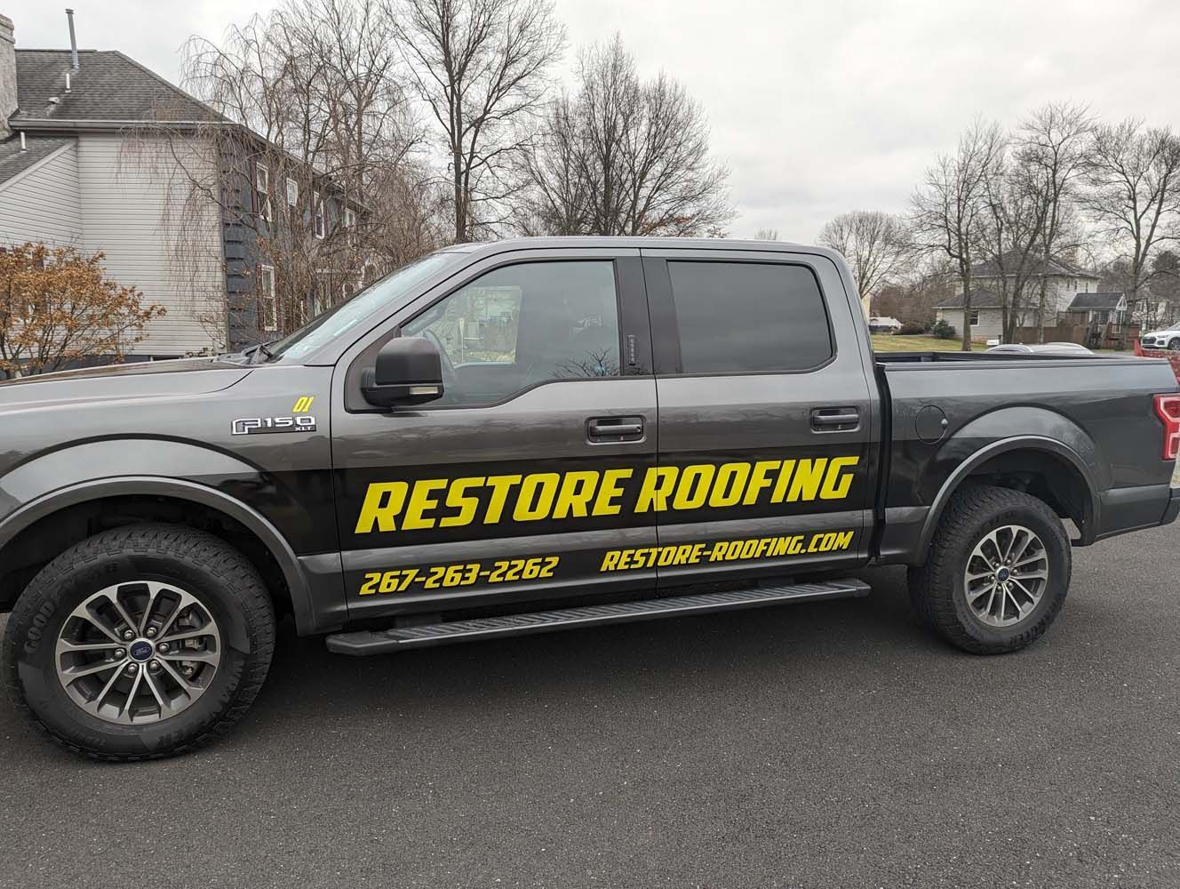 Gray Restore Roofing truck parked on a road.