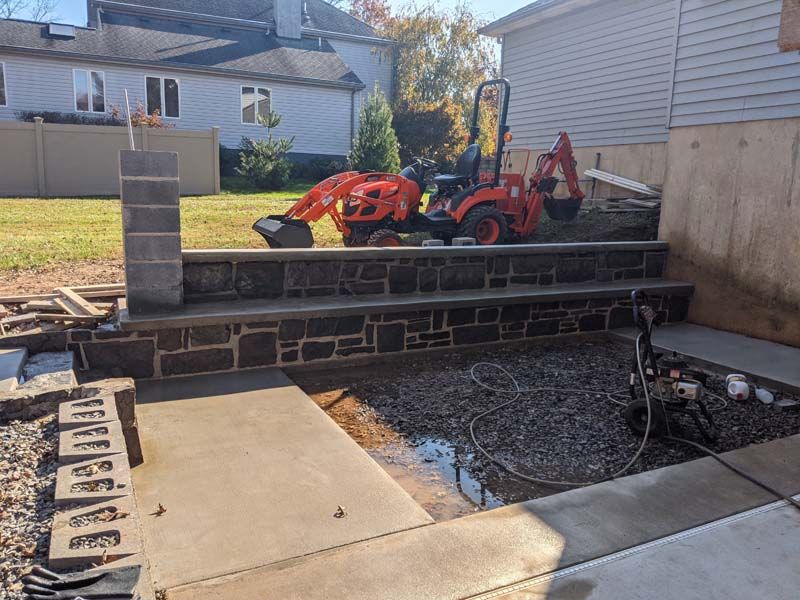 Construction site: Kubota tractor on stone steps, concrete work.