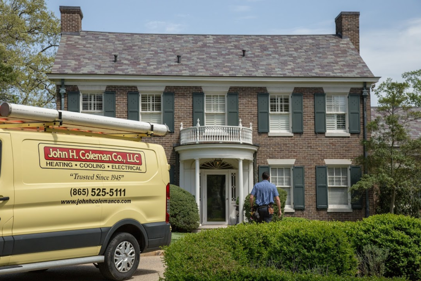A yellow van is parked in front of a large brick house.