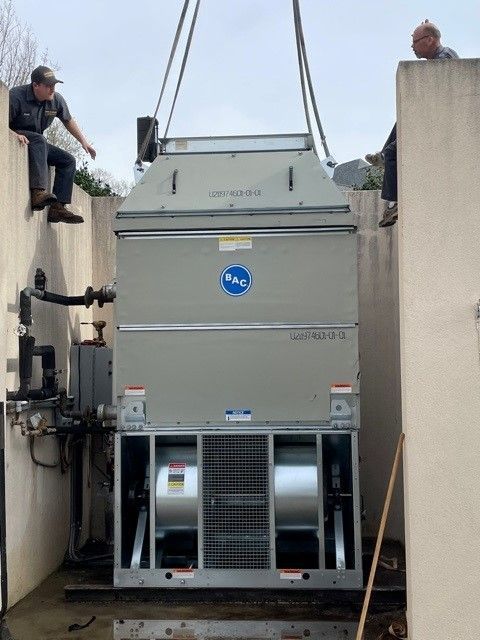 A man is sitting on a wall next to a large machine