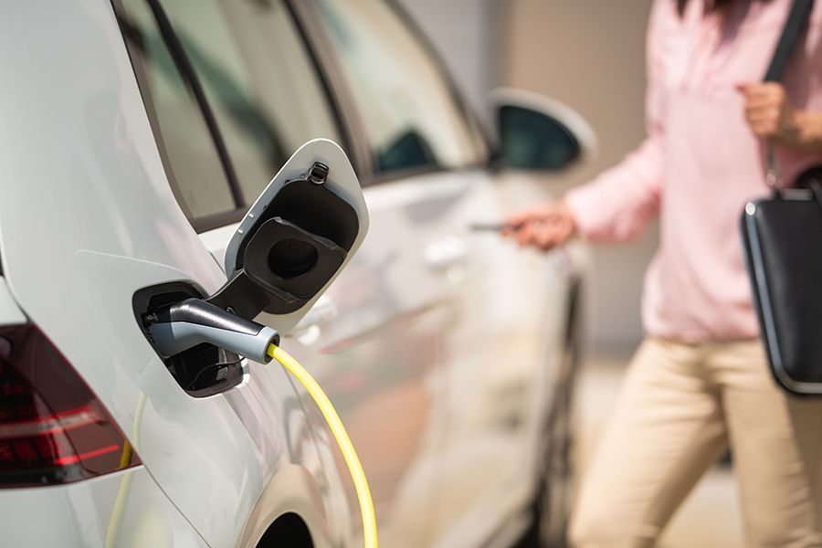 A woman is charging her electric car in the garage.