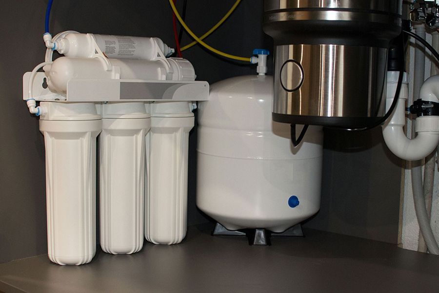 A water filter is sitting under a sink in a kitchen.