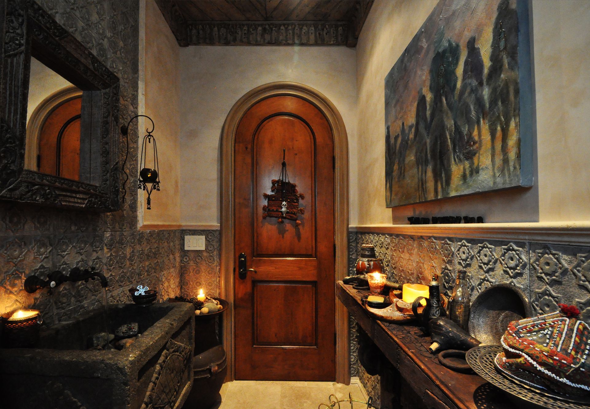 Ornate bathroom with dark wood door and sink, candles, and a painting of horses.