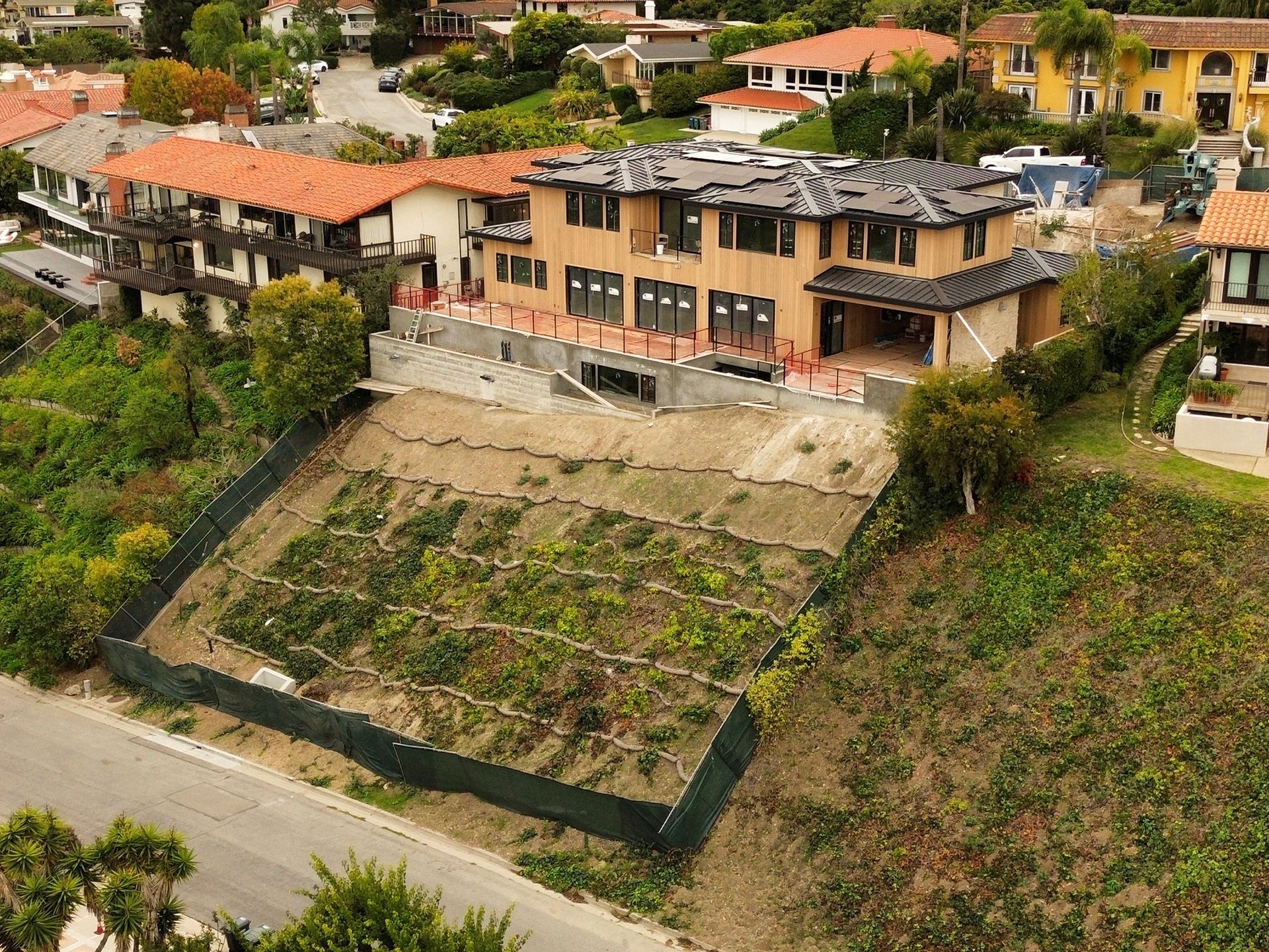 House under construction on a hillside lot with erosion control measures.