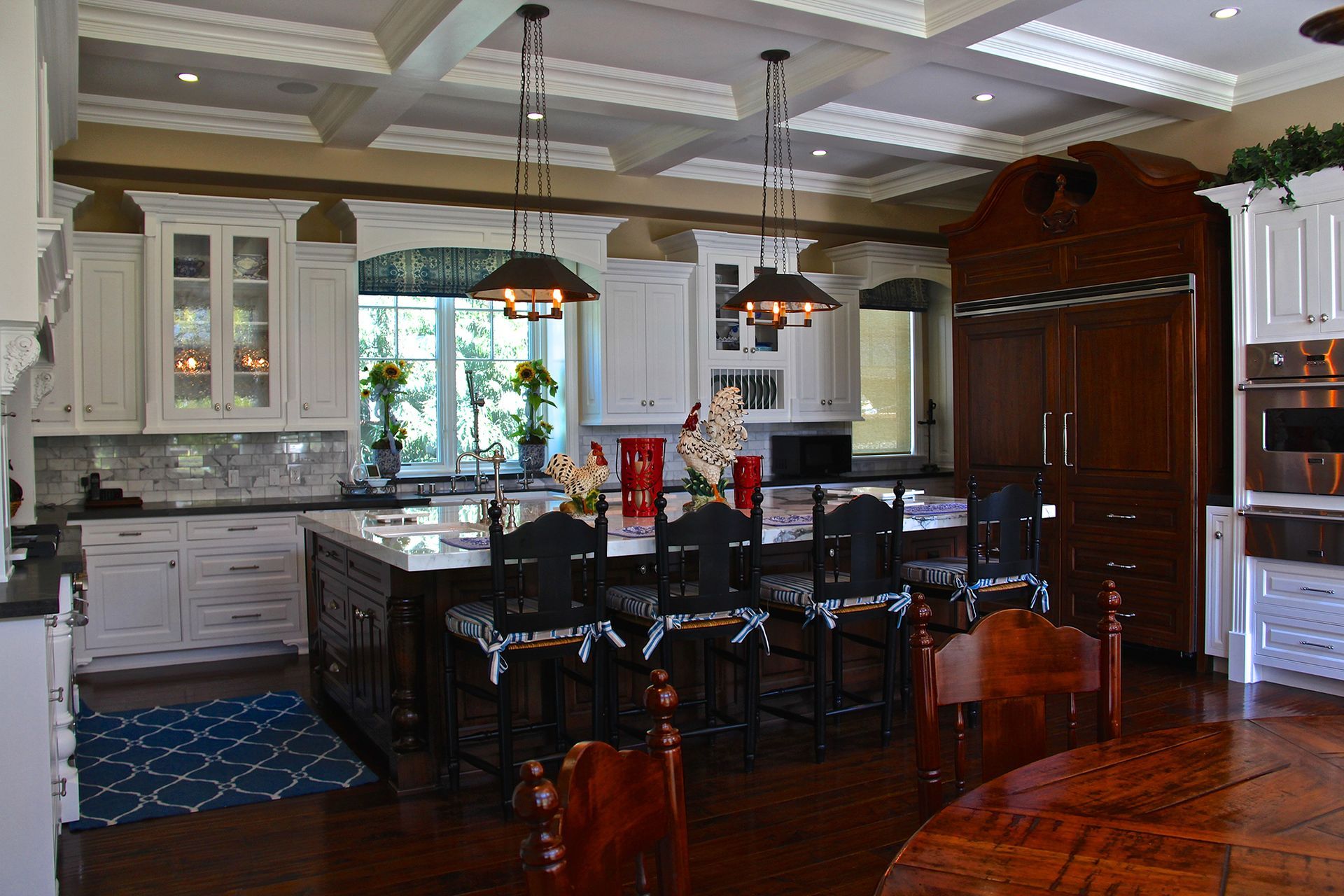 Kitchen with island, white cabinets, dark wood island, and pendant lights.