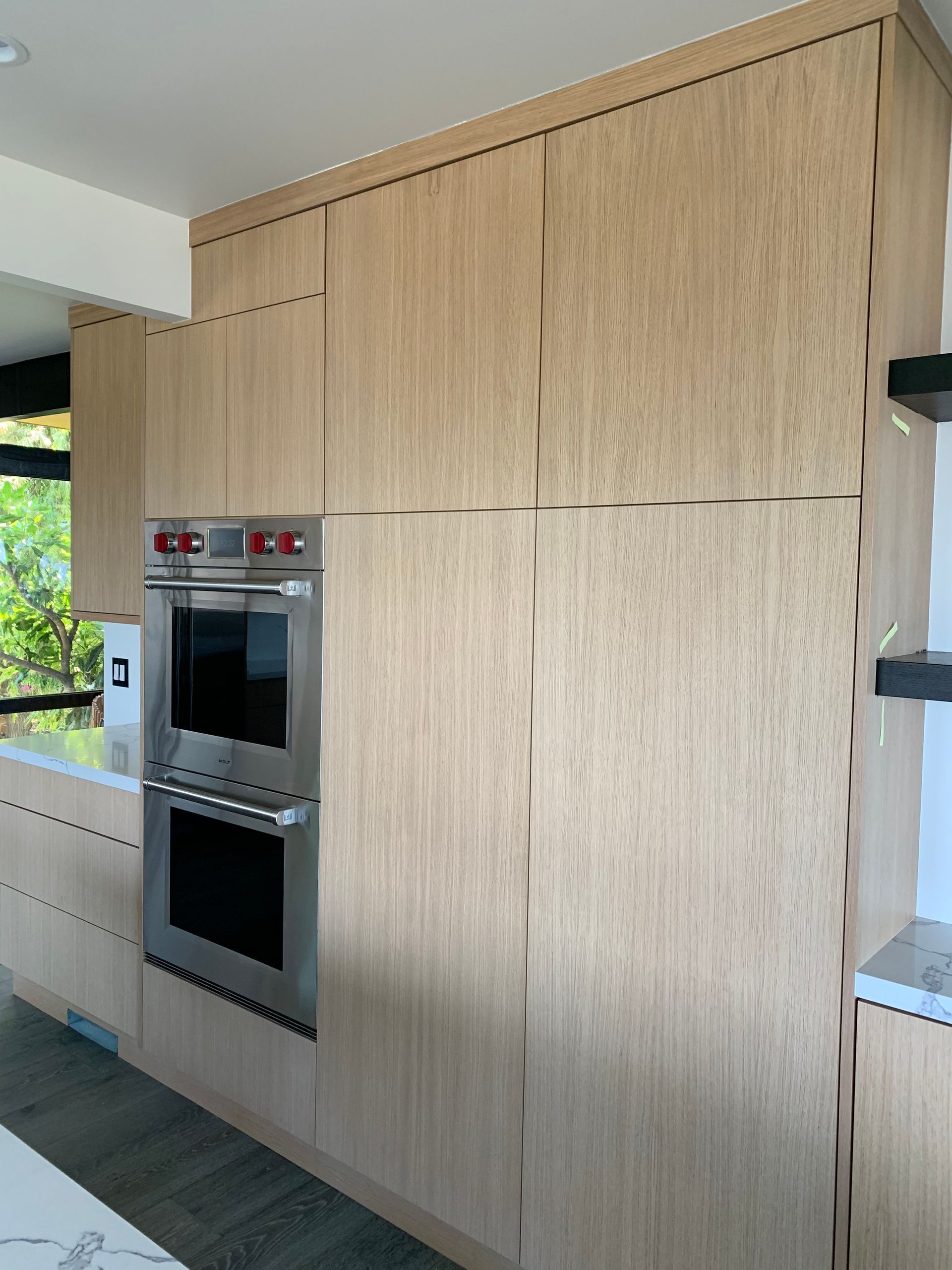 Light wood kitchen cabinets surround a stainless steel double oven.