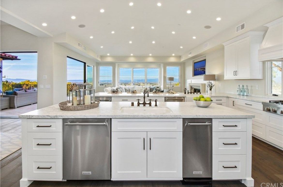 Spacious white kitchen with island, stainless steel appliances, and a view of the ocean.
