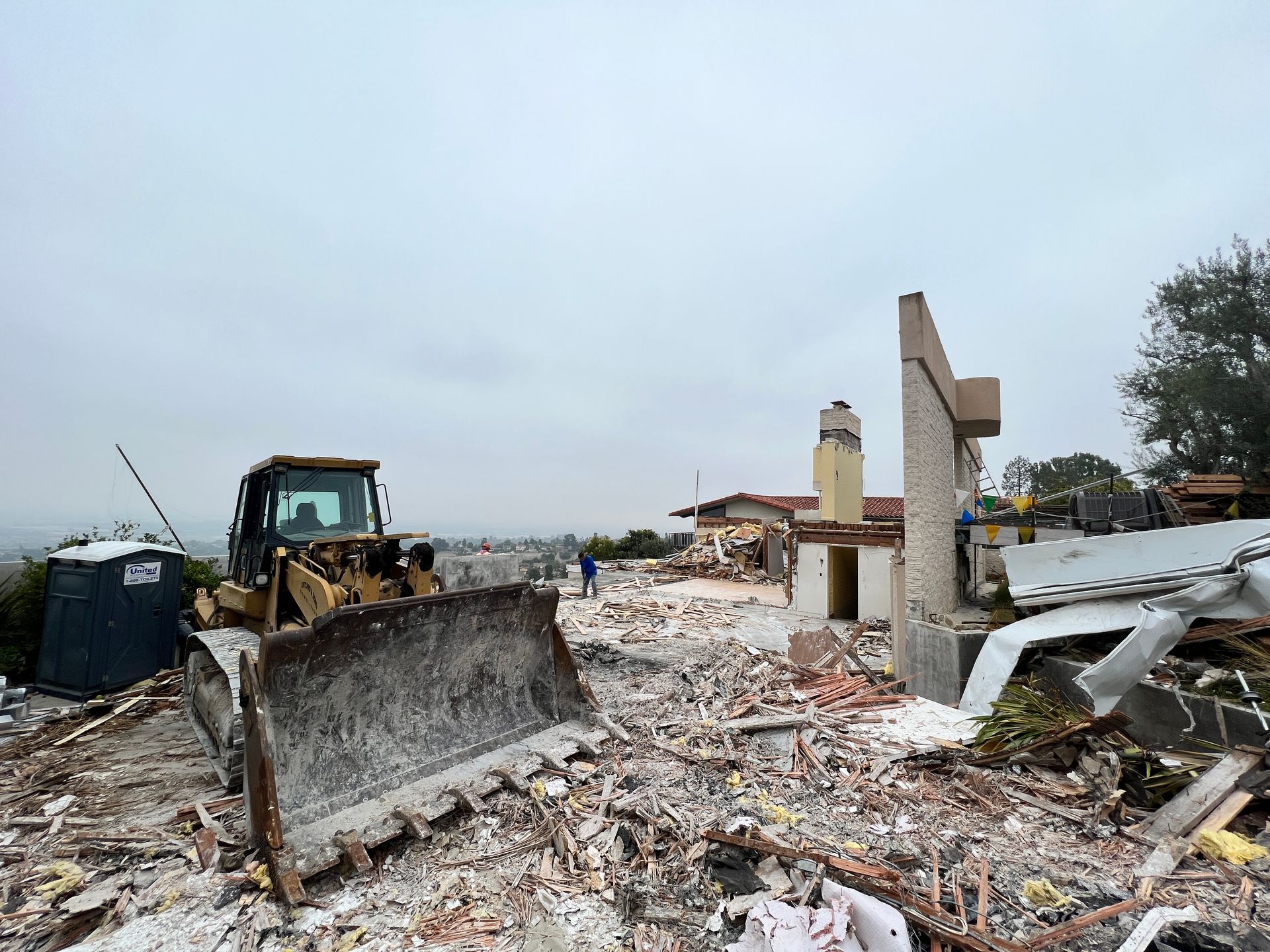 Bulldozer and debris from a demolished building, overcast sky.