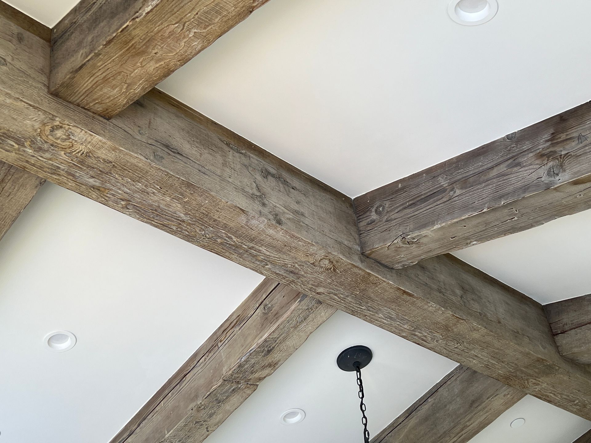 Wooden beams cross a white ceiling.