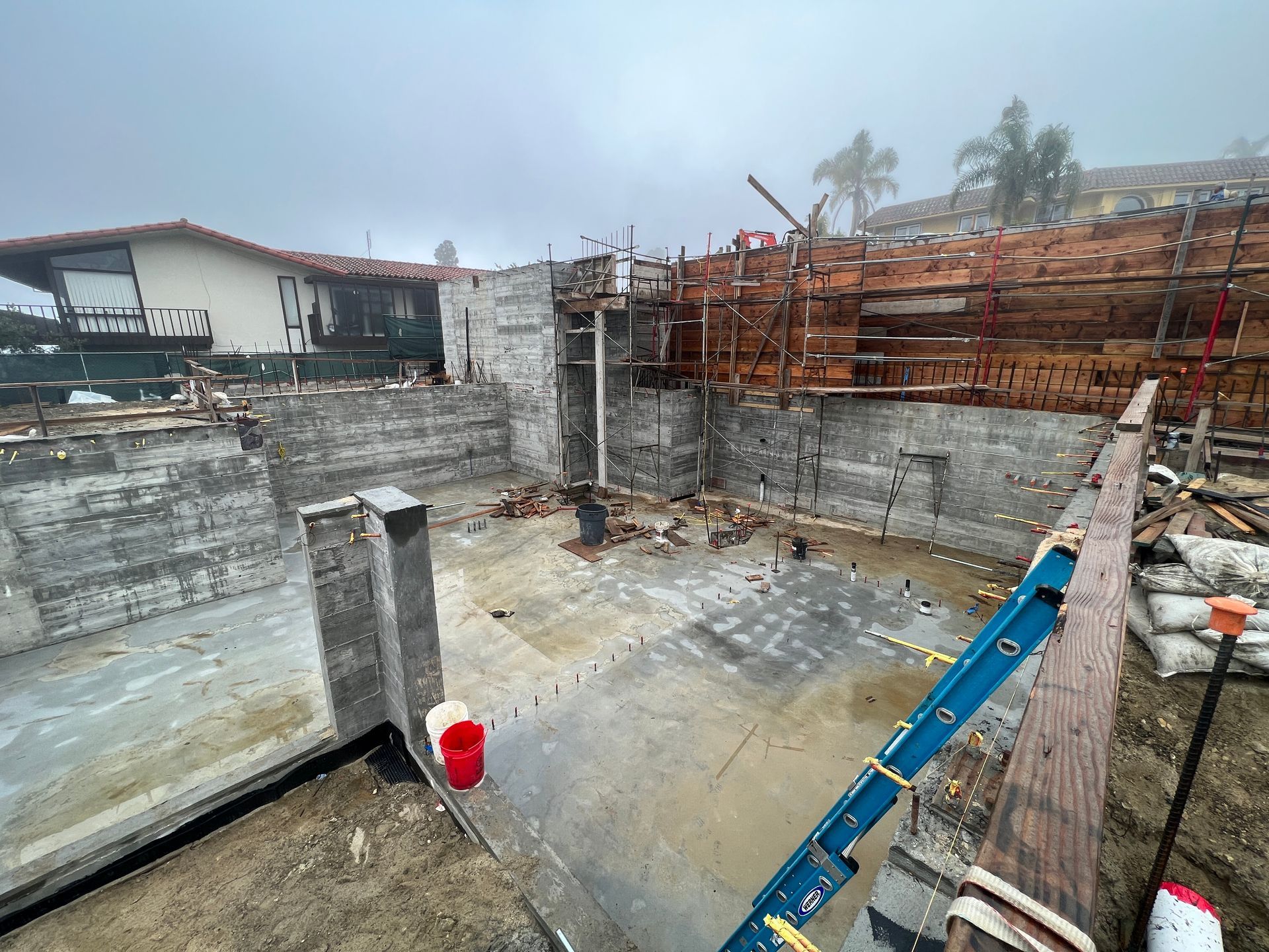 Construction site with concrete structures, wooden framework, and overcast sky.