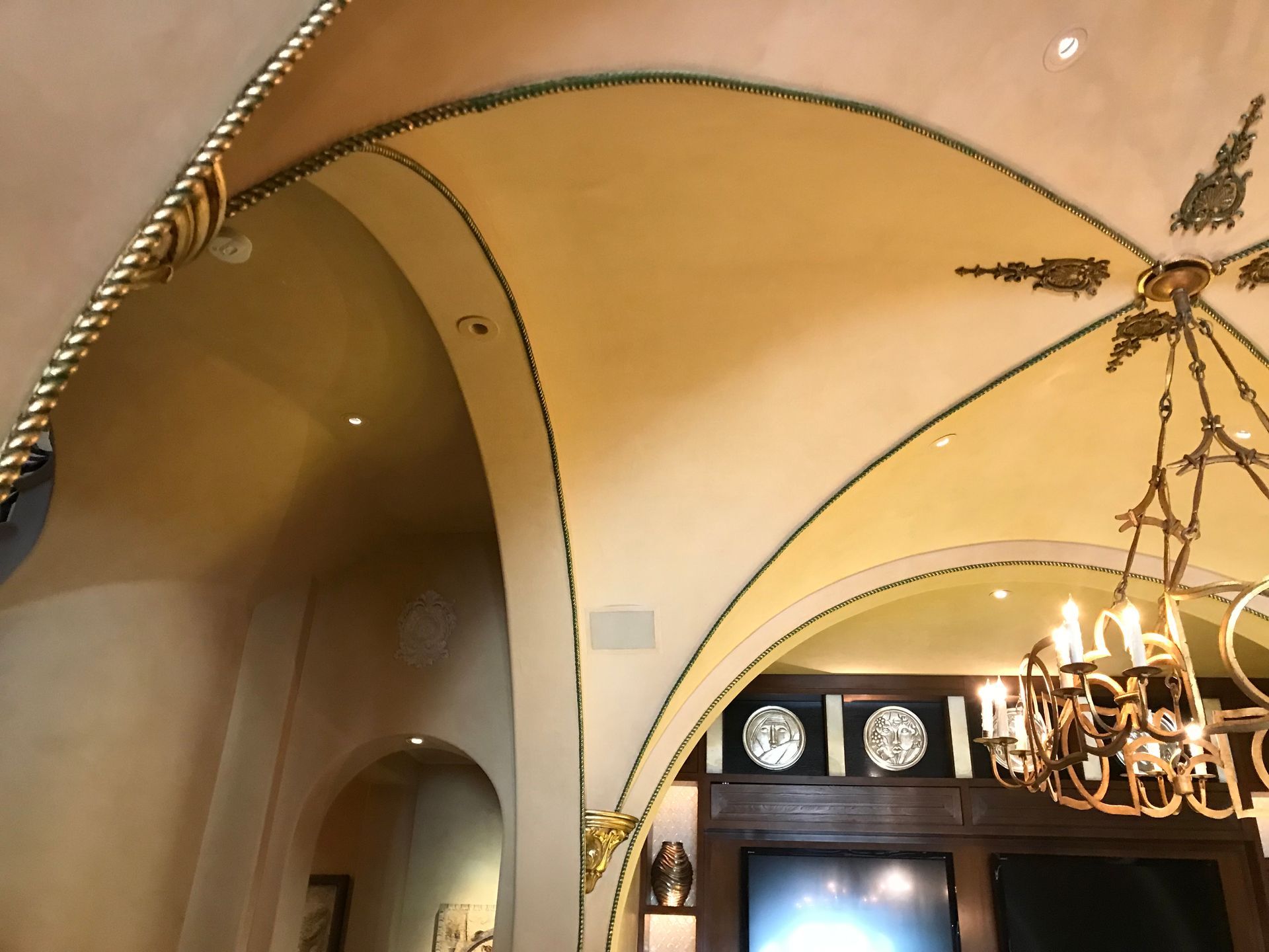 Ornate arched ceiling with gold trim and a chandelier.