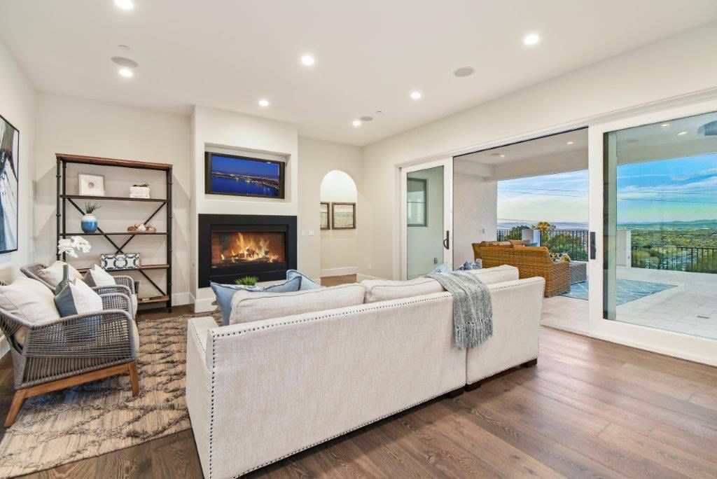 Living room with fireplace, white sectional, sliding door to patio with view.
