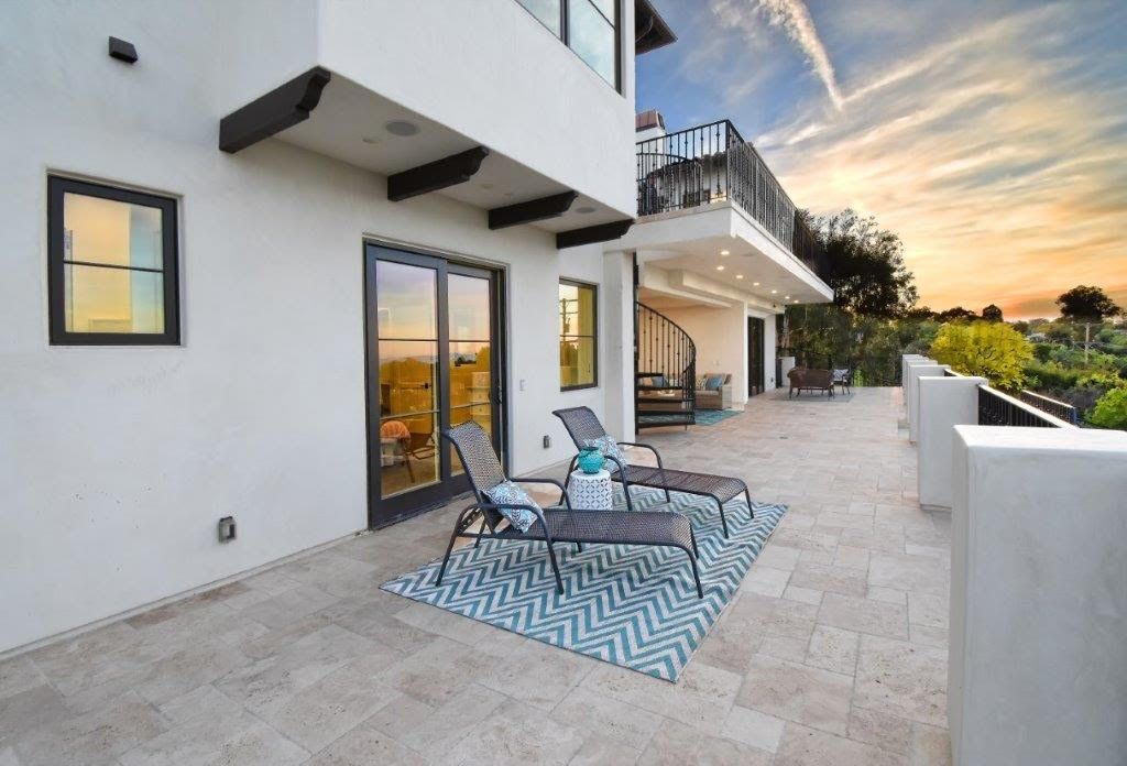 White stucco home with a patio, lounge chairs, and a sunset sky.