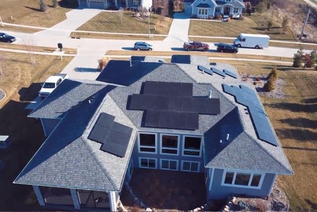 An aerial view of a house with solar panels on the roof