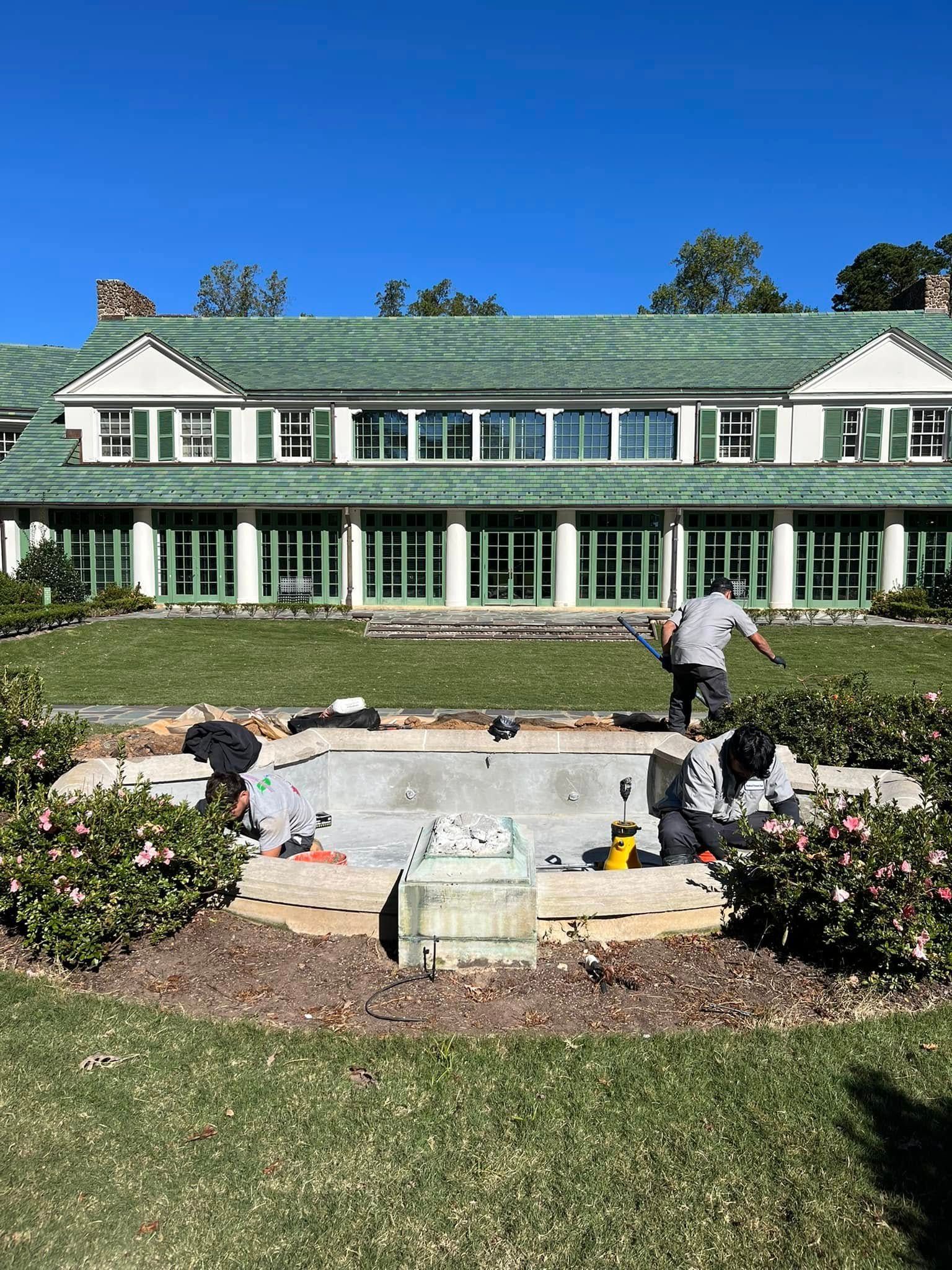 A group of people are working on a fountain in front of a large building.