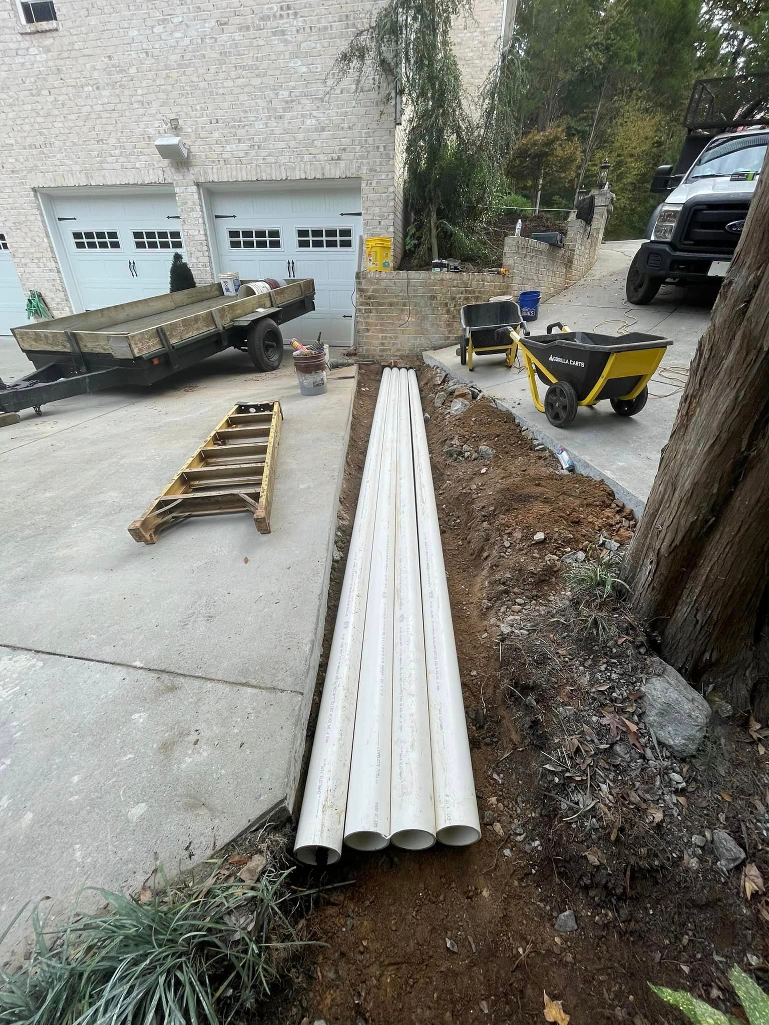 A bunch of pipes are sitting in the dirt in front of a house.