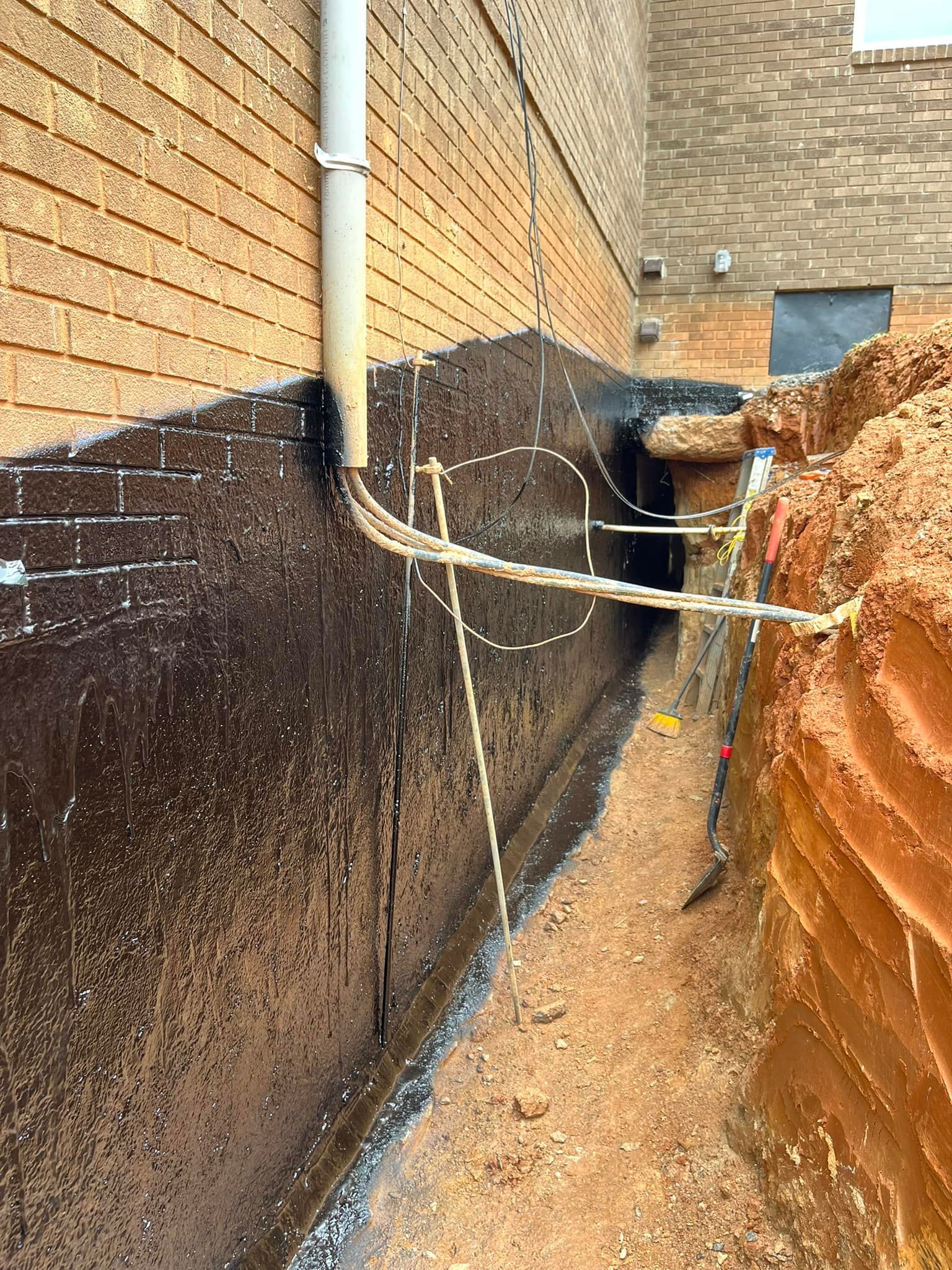 A drainage system is being installed on the side of a building.