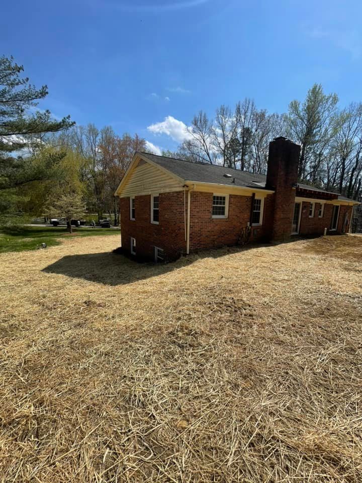 A brick house is sitting in the middle of a grassy field.