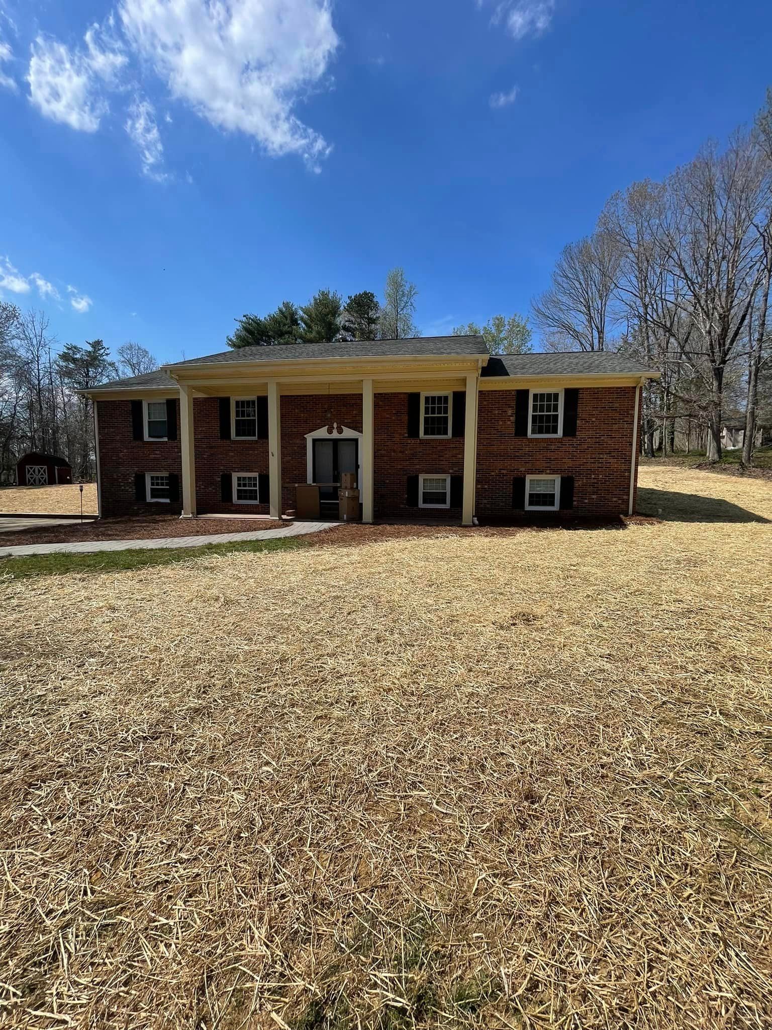 A large brick house is sitting in the middle of a field.