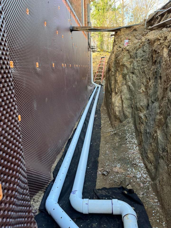 A drainage system is being installed on the side of a house.