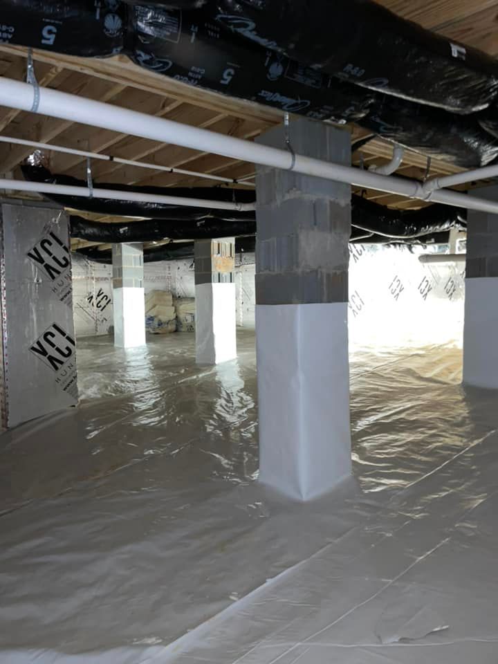 An empty basement with columns and pipes covered in plastic.