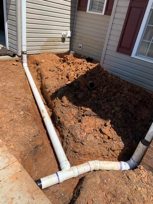 A drain pipe is being installed on the side of a house.