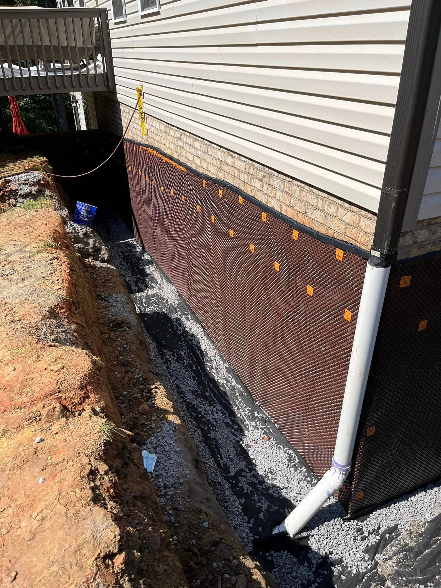 A drainage system is being installed on the side of a house.