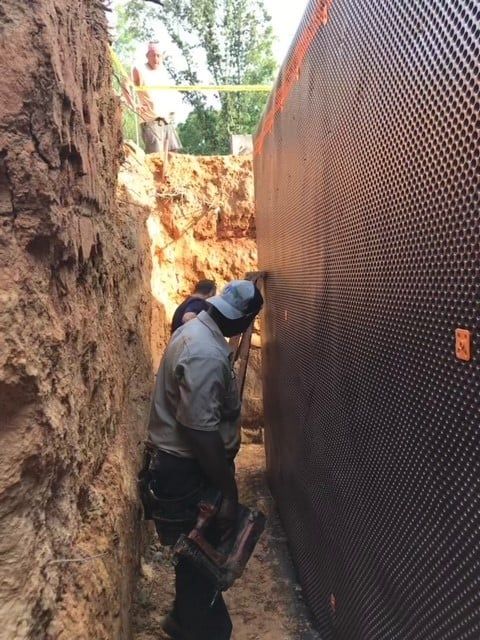 A man is working on a wall in a trench.