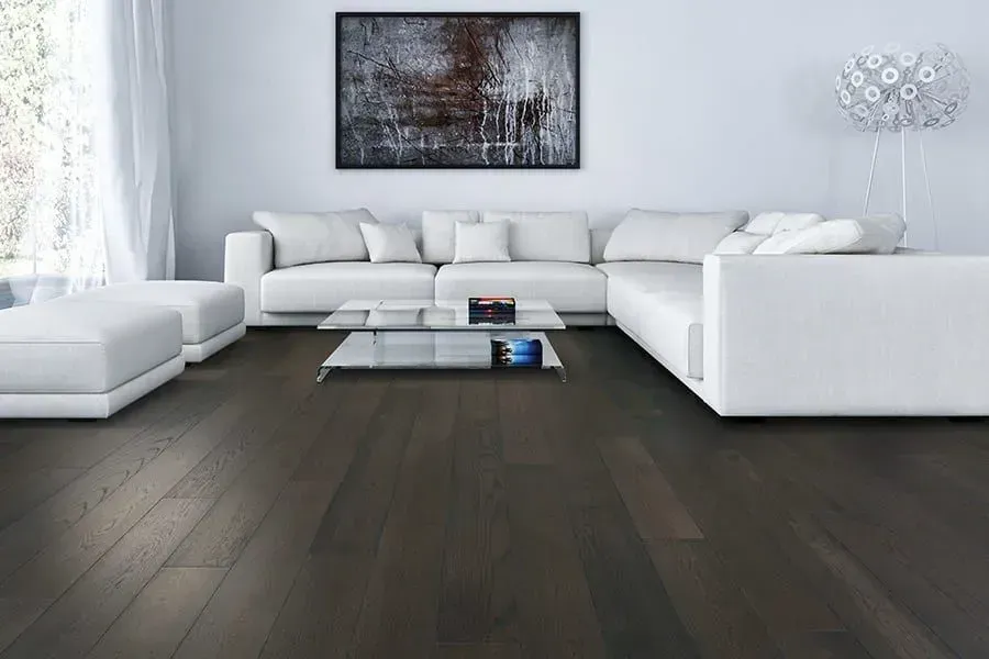 Modern living room with white sofa, dark wood floor, and abstract artwork.