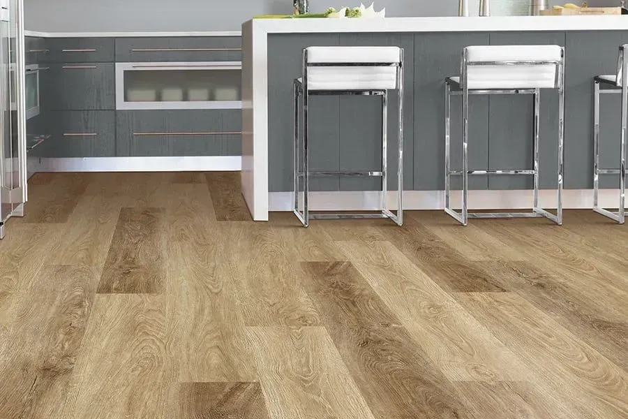Kitchen with light wood-look flooring and a gray island with chrome bar stools.