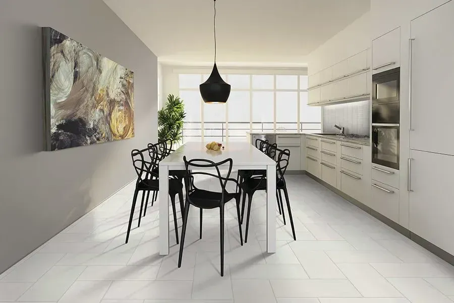 Modern kitchen and dining area with white cabinets, black chairs, and a long white table.