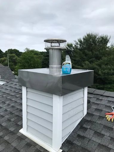 Rooftop vent with a metal chimney cap and a water bottle on a shingled roof