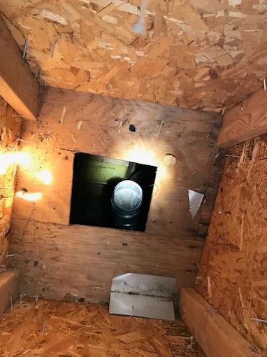 Wood-paneled shaft interior with a lit opening and a round pipe or duct at the far end
