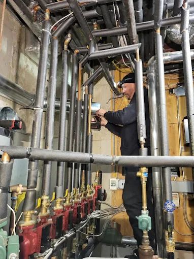 Worker inspecting pipes and valves in a mechanical utility room