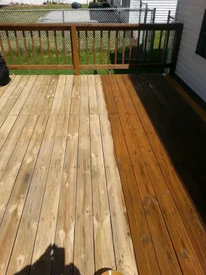 Wooden deck, half-treated with stain, showing the contrast between weathered wood and rich brown finish.