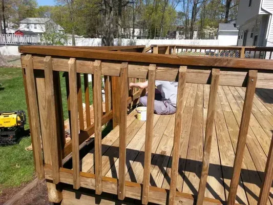 Wooden deck with a person staining the railing.