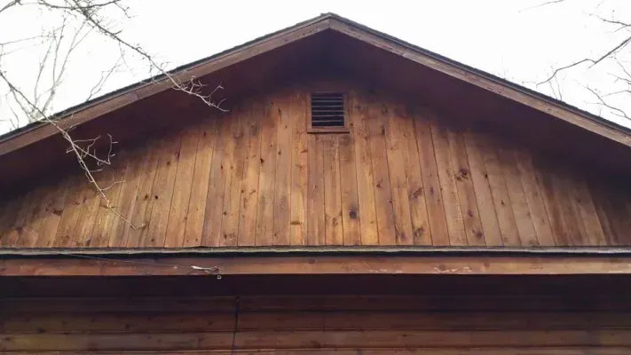 Wooden gable roof with a vent, viewed from below.