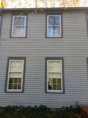 Two-story gray clapboard house with four white-framed windows. Dark gray trim.
