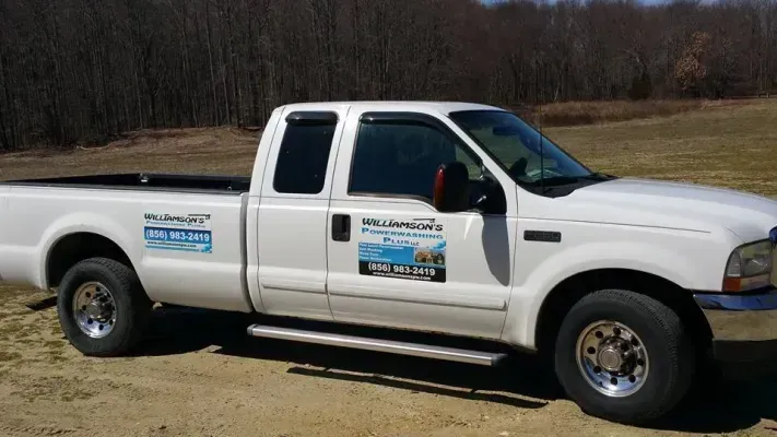 White pickup truck with company logos parked outdoors.