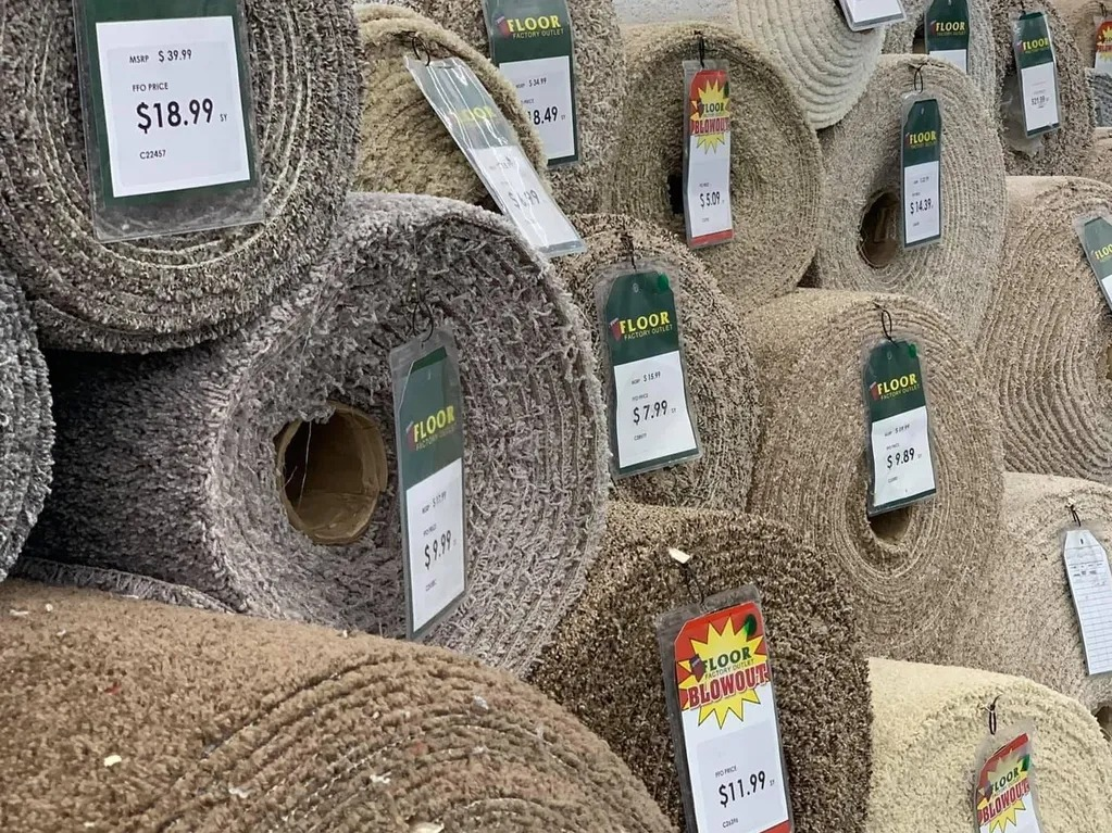 A collection of carpet rolls with pricing tags displayed in a store.