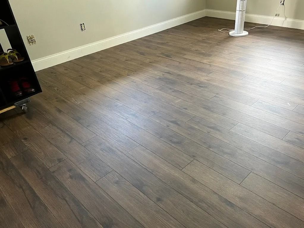 Dark brown wood-look flooring installed in a room with light-colored walls and baseboards.