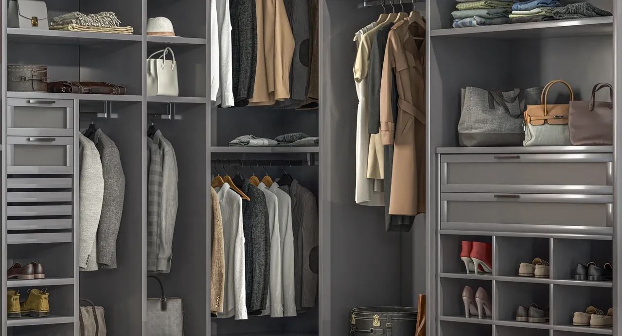A modern, organized gray walk-in closet with hanging clothes, drawers, open shelves for accessories, and shoe storage.