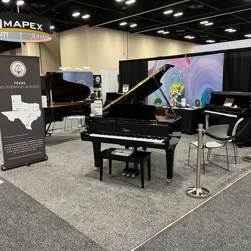A grand piano is sitting in a room with other pianos.